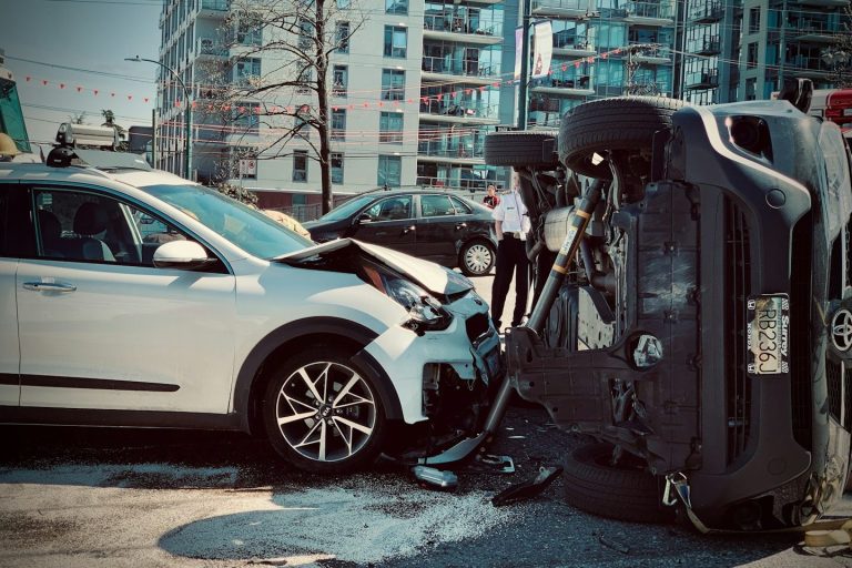 Unfall mit umgekipptem Auto und beschädigtem Fahrzeug auf der Straße.